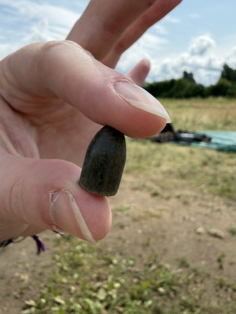 Bullet recovered during excavation of the Jungfernhof prisoner barracks foundation, held between a researcher’s fingers.