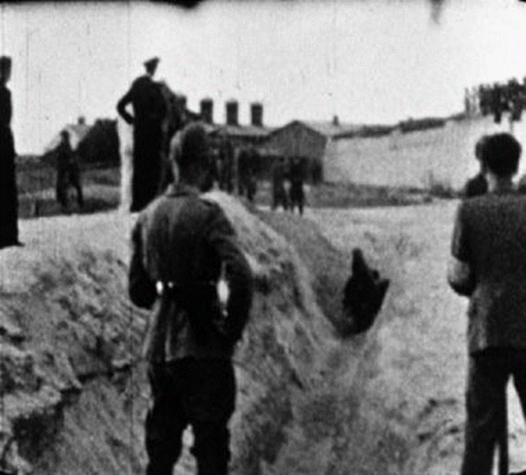 Historical still from the Wiener film showing armed personnel and Jewish men at a prepared burial trench near the Liepaja Lighthouse during a mass shooting.