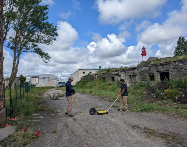 Researcher pushing ground-penetrating radar equipment along Grid 2 near the Liepaja fortification and lighthouse.